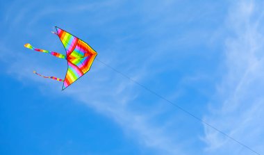 multicolored flying kite toy vibrating in the blue sky symbol of freedom joy