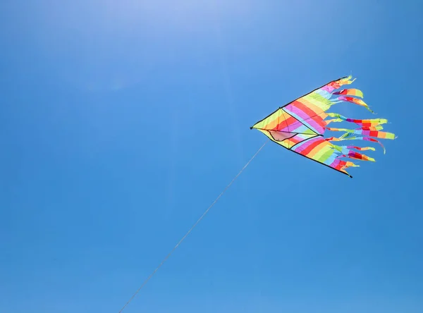 multicolored flying kite toy vibrating in the blue sky symbol of freedom joy