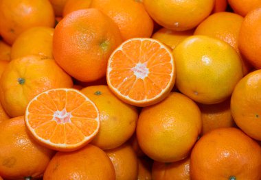 background of many ripe orange clementines or tangerines and some cut in half