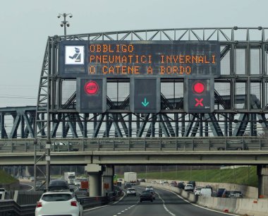 Wide Signal in the Motorway with text that means obligation winter equiment or  chains snow in Italian Language