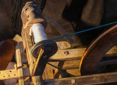 wooden spinning wheel with skein of thread in an old attic of the rural house