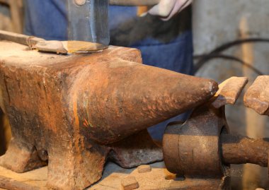 rusted iron anvil and hammer that seems to be moving in the blacksmiths workshop