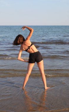 young girl during training by the sea in summer with shorts