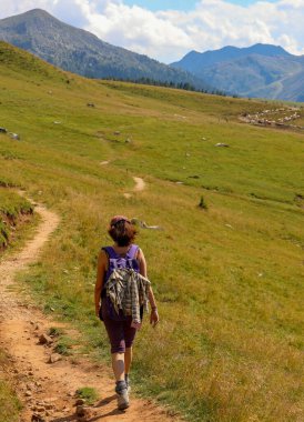 young woman walks on the path in the mountains in summer