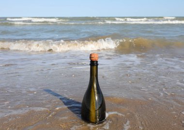 Bottle of green green on the rive of the sea without people with cork cap