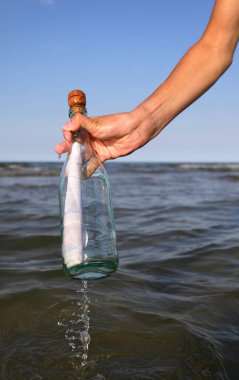hand picking up a glass bottle with maybe a secret treasure map