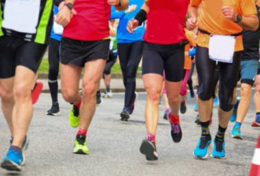 Asfalt yolda koşarken kasten spor kıyafetleriyle koşan bir grup bulanık sporcu.