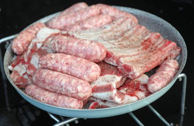 Çiğ sosis ve domuz pirzolası dışarıda ızgara yapmaya hazır.