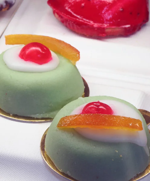 handcrafted desserts made of pistachio and garnished with orange zest and black cherry
