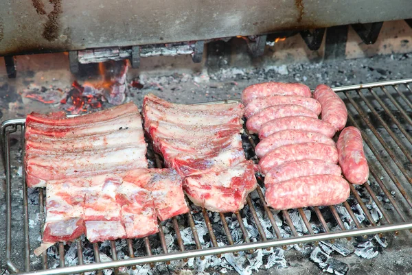 生ソーセージと豚バラ肉を屋外のバーベキューで焼く準備ができています — ストック写真