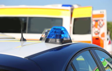 Şehirdeki bir trafik kazası sırasında polis arabasının arka planında mavi yanıp sönen ışıklar.