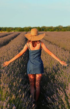 Hasır şapkalı, lavanta tarlasında kot etek giyen genç, narin bir kız.