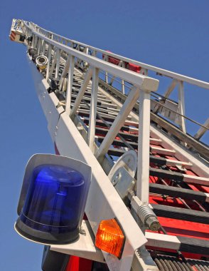 İtfaiye merdiveninin uzun metal merdiveni ve egzersiz sırasında mavi parlayan ışık.