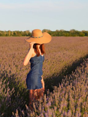 Hasır şapkalı, lavanta tarlasında kot etek giyen genç, narin bir kız.