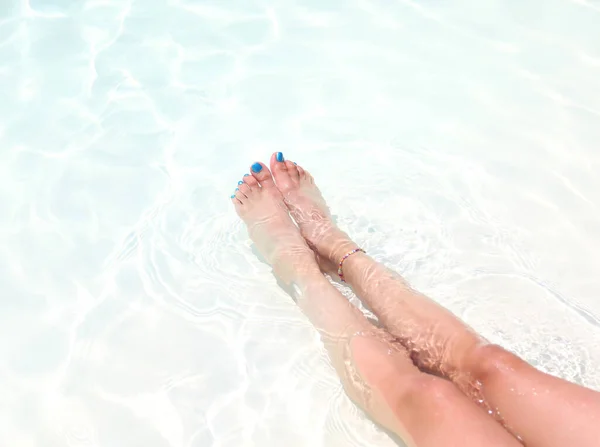 slender legs of the woman relaxing in the water and toenails with polish