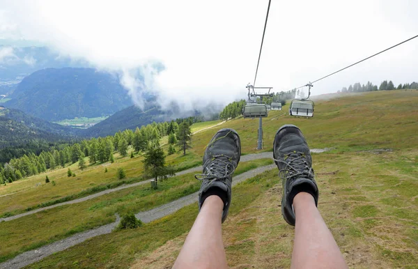 feet of the hiker being carried by a chair lift during high mountain excursions