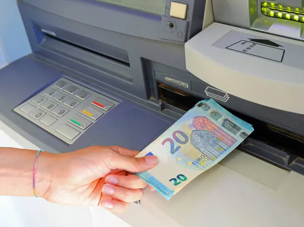 girl takes money from automatic teller machine in european twenty euro banknotes