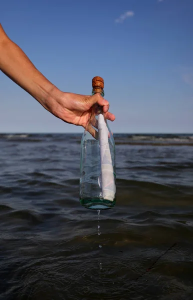 boy takes a bottle with a secret message on the sea in summer