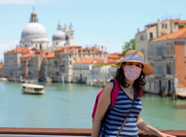 İtalya 'daki tecrit sırasında Venedik' i ziyaret eden maskeli ve hasır şapkalı güzel bir genç kadın turist.