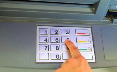 Bankamatik hizmetlerine erişmek için gizli PIN kodunu yazan bir gencin eli.