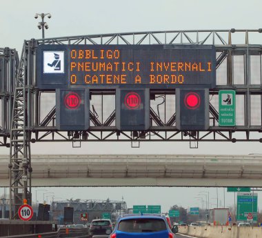 İtalyanca metni olan yol işareti kış ekipmanları ve hız tespit kameraları zorunluluğu anlamına gelir