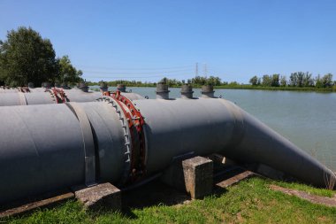 Nehir taşkınlarını önlemek ve kuraklık dönemlerinde tarlaları sulamak için endüstriyel kanalları kurutmak için Idrovore 'dan metal borular.