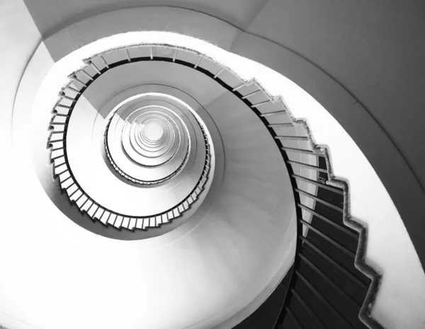 Spiral staircase seen in perspective with the steps going towards infinity in black and white