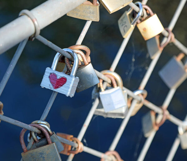 many Padlocks attached to the bridge by lovers and one with a red heart drawn
