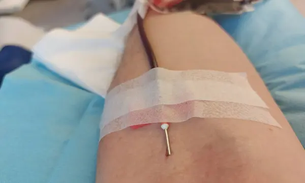 Caucasian man with needle stuck in arm at hospital during free blood donation
