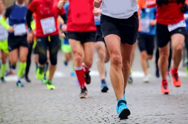 Şehir sokaklarında maraton koşan birçok insanın bacakları.