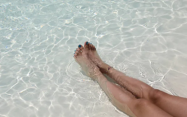 Young womans legs relaxing on the water with toenails colored with nail polish