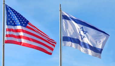 İki büyük İsrail ve Amerikan bayrakları mavi gökyüzünde insanlar olmadan dalgalanıyor.