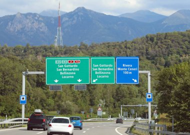 Otobanda yol işaretleri olan bir portal. İsviçre 'de İtalyan sınırına yakın birçok yerin yönünü gösteriyor.