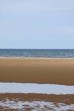 Okyanus suyunun arka planı kumsalda kum ve su birikintisi yansıması