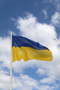 Sarı ve mavi renkli büyük dalgalı Ukrayna bayrağı ve arka planda gökyüzü olan bulutlar