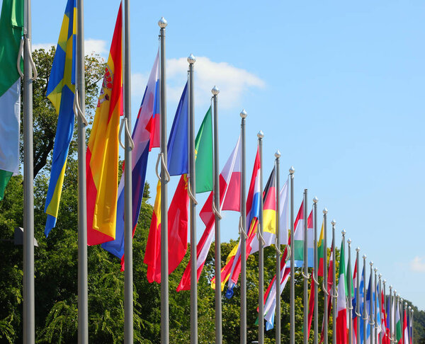 many colorful flags of world states lined up on poles during the international event