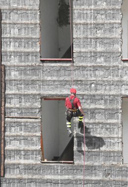 Kırmızı miğferli cesur itfaiyeci yıkılmış bir binanın üzerinden tırmanıyor.