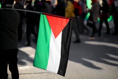 Filistin bayrağı arka planda ve şehirdeki barışçıl protesto sırasında birçok insan