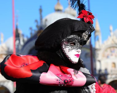 Venedik Karnavalı sırasında maskeli kadın St. Mark SQuare 'de ve arka plandaki eski bazilika...