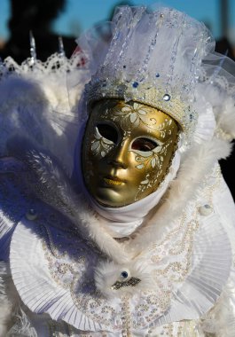 Venedik Karnavalı sırasında altın maskeli ve beyaz tarihi elbiseli maskeli biri.