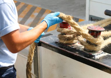 Uzman denizci gemiyi bağlamak için ipi yakalar ve iskeleye bağlar.