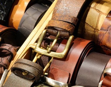 Metal tokalı zanaatkarlar tarafından üretilen deri kemerler deri eşya mağazasında satılmaktadır.