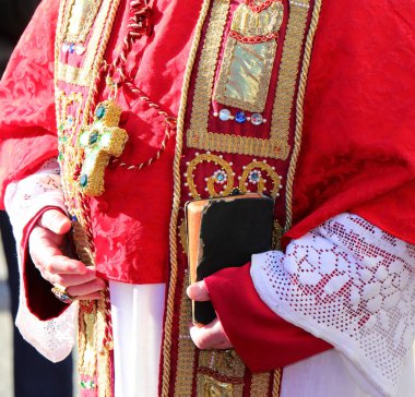 Dini ayin sırasında piskoposun elinde kutsal yazılar ve kırmızı papaz elbisesi olan İncil.