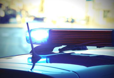 Polis arabası sirenleri yol barikatı boyunca mavi yanıp sönüyor.