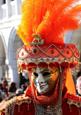 Venedik, VE, İtalya - 13 Şubat 2024: Venedik Karnavalı sırasında altın ve beyaz msk ve kafasında turuncu tüyler