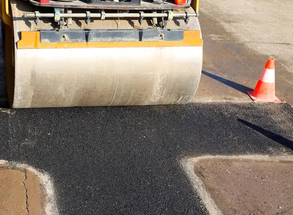 Bir trafik konisi ve asfalt silindirli inşaat alanı