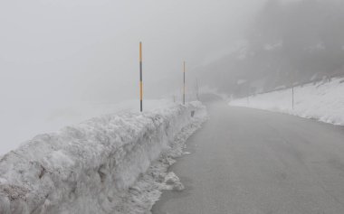 Yoğun sis ve kenarlarında kar nedeniyle görüş mesafesi düşük buzlu dağ yolu.