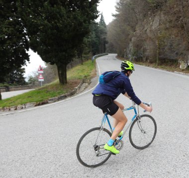 Başında koruyucu miğferiyle bisikletçi pedallarla dağların tepesinde bisiklet sürüyor.