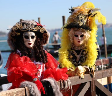 Venice, VE, Italy - February 13, 2024: two masked women at Venetian Carnival in Venetian lagoon clipart