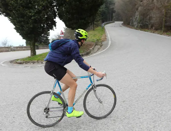 young cyclist pedals on uphill road with racing bike during mountain cycling race
